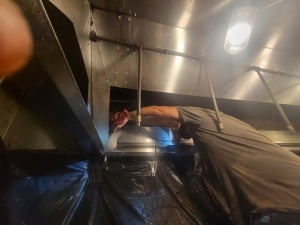 Image of a kitchen hood exhaust being cleaned by a professional.