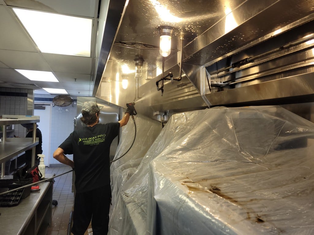 Professional cleaner power washing a commercial kitchen exhaust hood using an antimicrobial solution in Hawaii. Oahu restaurant exhaust hood cleaning Honolulu. Exhaust hood cleaning service in Oahu.